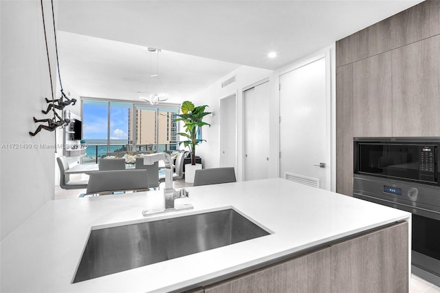 kitchen featuring expansive windows, sink, decorative light fixtures, wall oven, and black microwave