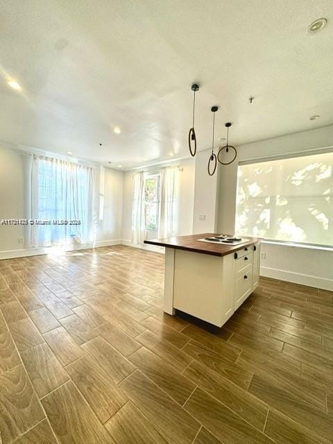 kitchen featuring white cabinets, pendant lighting, a center island, and white gas stovetop