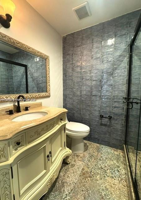 bathroom with vanity, toilet, and a shower with shower door