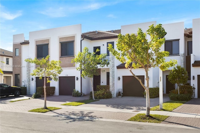 townhome / multi-family property featuring a garage, driveway, and stucco siding