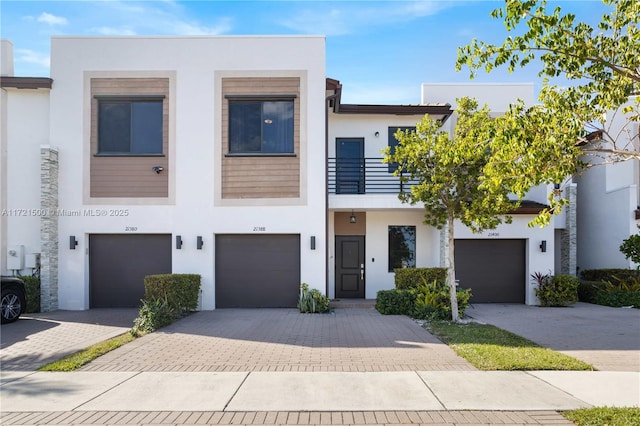 view of front of home featuring decorative driveway, a balcony, and stucco siding