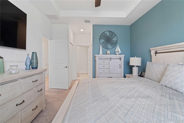 bedroom featuring light carpet, visible vents, and a tray ceiling