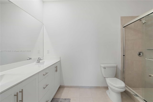 bathroom featuring a stall shower, a sink, toilet, and tile patterned floors