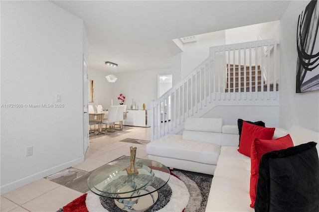 living area with stairs, baseboards, and tile patterned floors