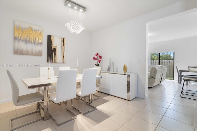 dining room featuring light tile patterned floors, baseboards, and an inviting chandelier