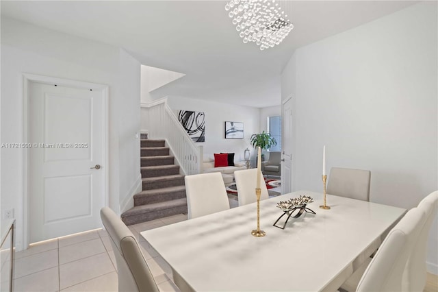 dining room featuring an inviting chandelier, stairway, and light tile patterned flooring