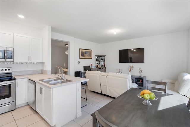 kitchen featuring open floor plan, stainless steel appliances, a peninsula, and a sink