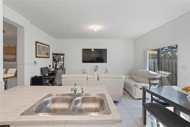 kitchen with light tile patterned floors, light countertops, a sink, and open floor plan