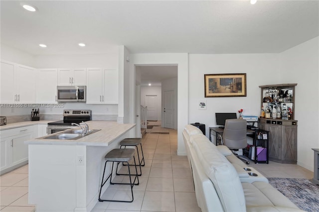 kitchen with stainless steel appliances, light tile patterned flooring, a breakfast bar area, and white cabinetry