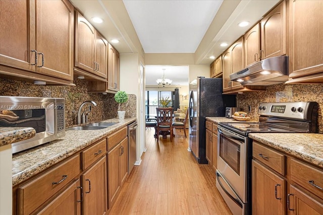 kitchen featuring sink, light stone countertops, tasteful backsplash, a notable chandelier, and stainless steel appliances