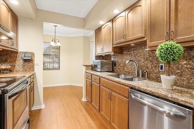 kitchen with sink, stainless steel appliances, an inviting chandelier, stone countertops, and light wood-type flooring