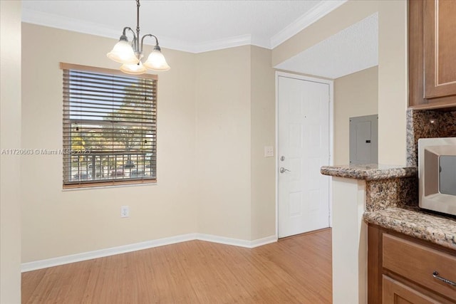 unfurnished dining area featuring electric panel, crown molding, light wood-type flooring, and an inviting chandelier