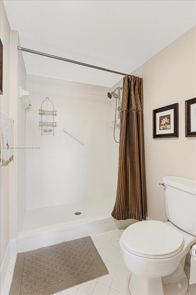 bathroom featuring tile patterned floors, toilet, and walk in shower