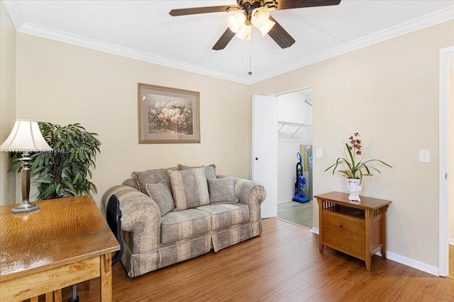 living room with wood-type flooring, ceiling fan, and crown molding