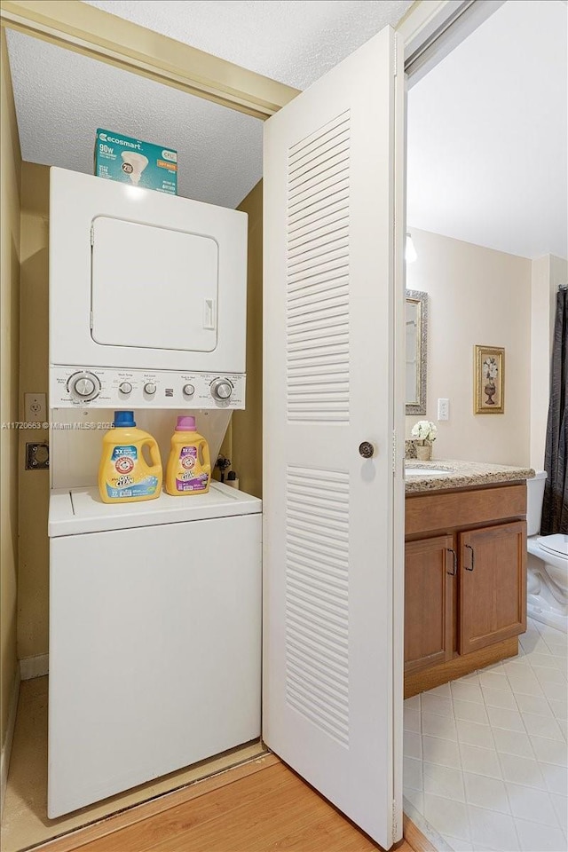 laundry room with stacked washer / drying machine and a textured ceiling