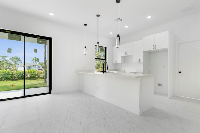 kitchen with kitchen peninsula, decorative light fixtures, white cabinetry, and plenty of natural light