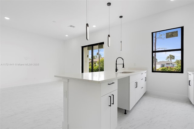 kitchen featuring white cabinetry, sink, and pendant lighting