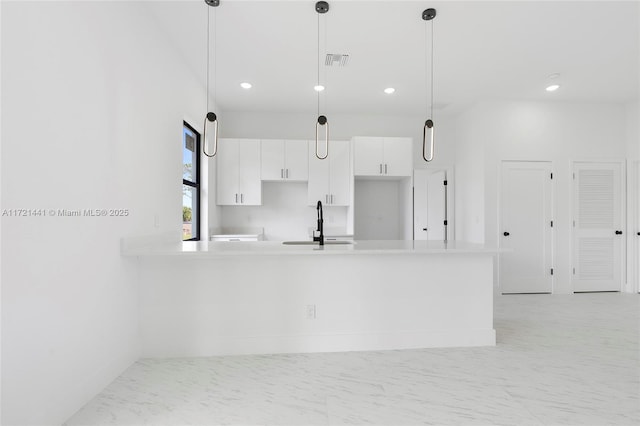 kitchen with kitchen peninsula, sink, white cabinetry, and hanging light fixtures