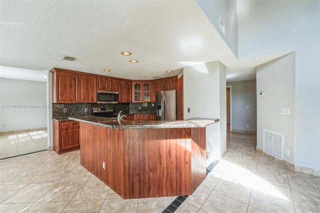 kitchen with sink, light tile patterned floors, decorative backsplash, dark stone counters, and appliances with stainless steel finishes