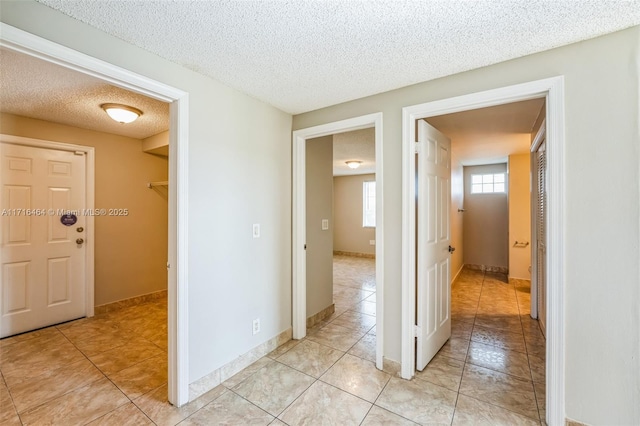 hall with a textured ceiling and light tile patterned floors