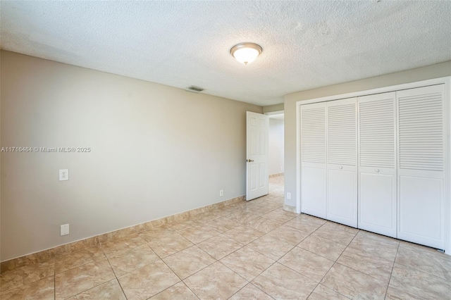 unfurnished bedroom featuring light tile patterned flooring, a closet, and a textured ceiling