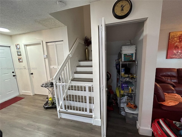 stairway with a textured ceiling and hardwood / wood-style flooring