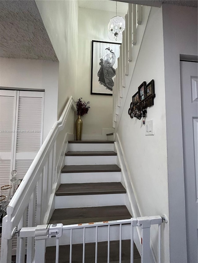 staircase with a notable chandelier