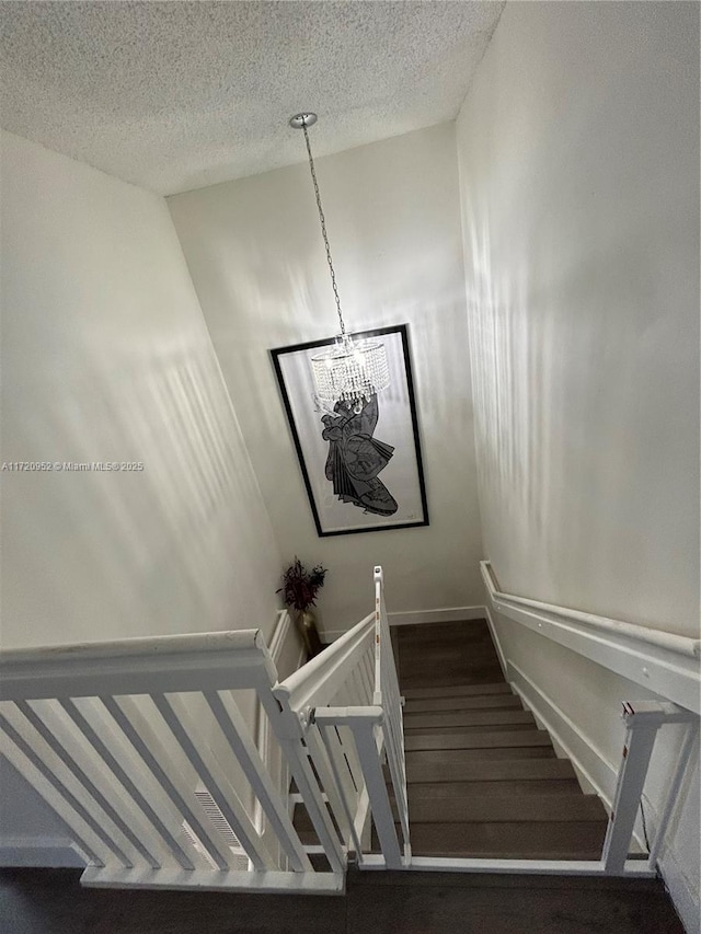 staircase with a textured ceiling and an inviting chandelier