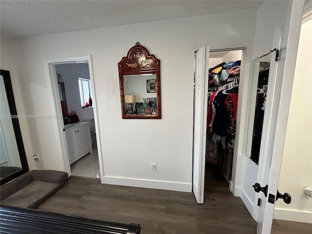 bedroom featuring a textured ceiling, ensuite bathroom, a closet, and dark hardwood / wood-style floors