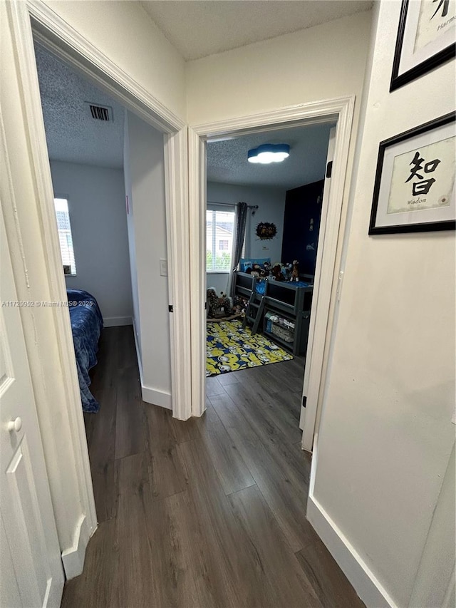 corridor with dark hardwood / wood-style flooring and a textured ceiling