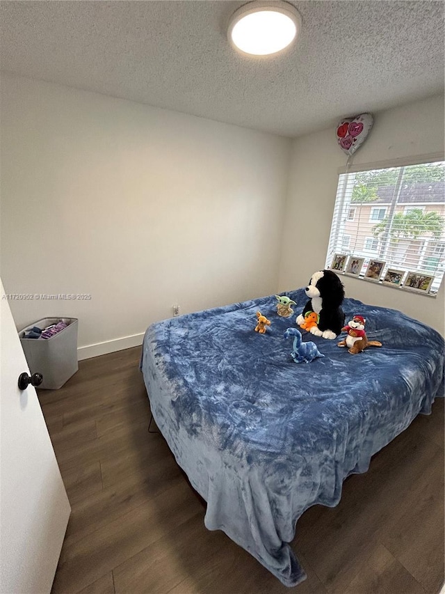 bedroom with dark hardwood / wood-style flooring and a textured ceiling