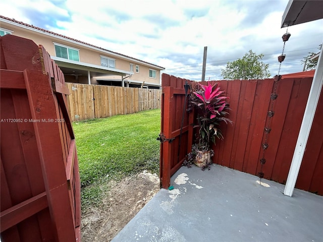 view of gate featuring a lawn and a patio area