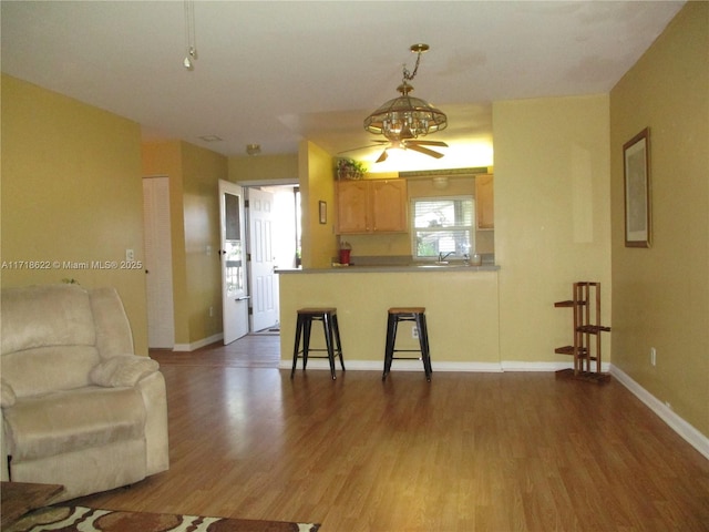 kitchen featuring ceiling fan, a kitchen breakfast bar, dark hardwood / wood-style flooring, kitchen peninsula, and light brown cabinetry