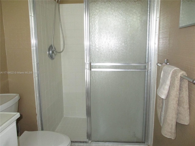 bathroom with a shower with shower door and toilet