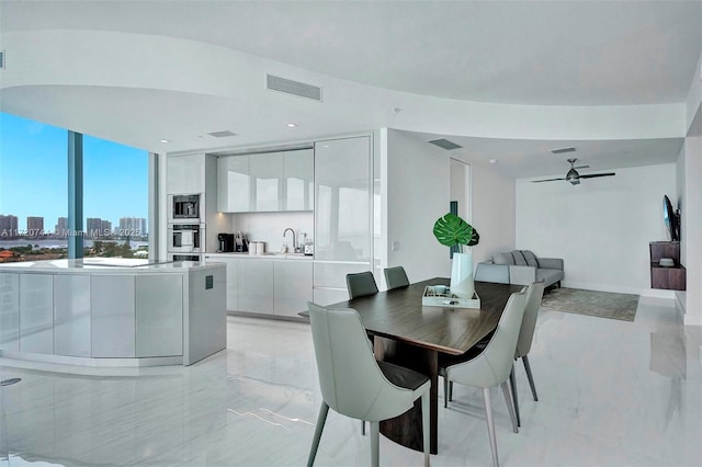 dining area with ceiling fan, a wall of windows, and sink