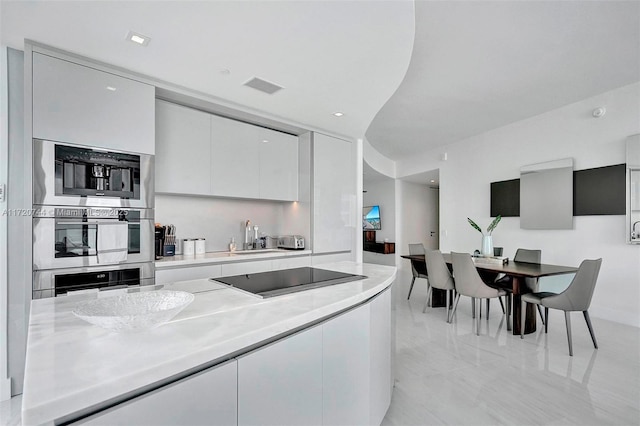 kitchen with white cabinets, stainless steel double oven, black electric cooktop, and sink