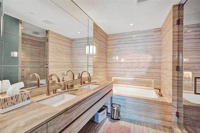 bathroom featuring vanity, tile walls, and shower with separate bathtub