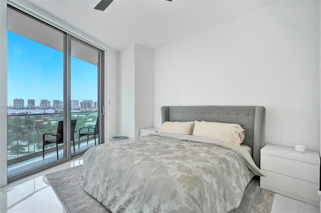 bedroom featuring ceiling fan, expansive windows, light tile patterned floors, and access to outside