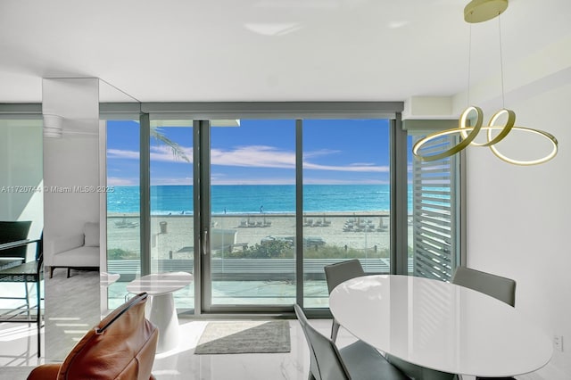 interior space with a water view, a wall of windows, and a view of the beach