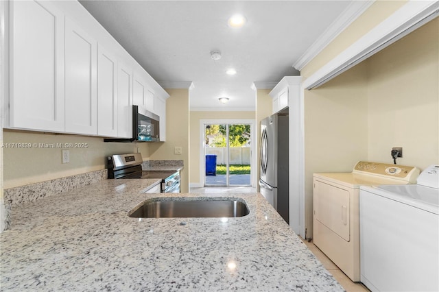 kitchen with white cabinetry, light stone countertops, washer and clothes dryer, appliances with stainless steel finishes, and ornamental molding