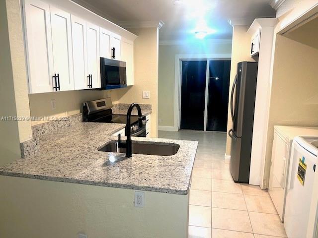 1574 NW 7th Ln, Pompano Beach, FL 33060 - kitchen featuring stainless steel appliances, crown molding, light stone counters, washer and clothes dryer, and white cabinetry