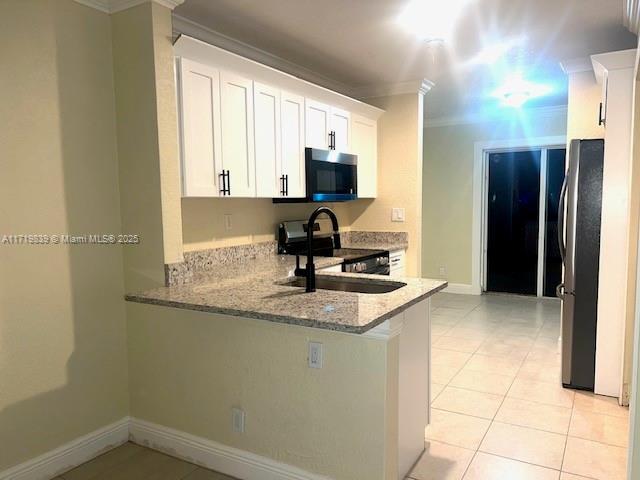 1574 NW 7th Ln, Pompano Beach, FL 33060 - kitchen featuring stainless steel appliances, crown molding, light stone countertops, light tile patterned flooring, and white cabinets