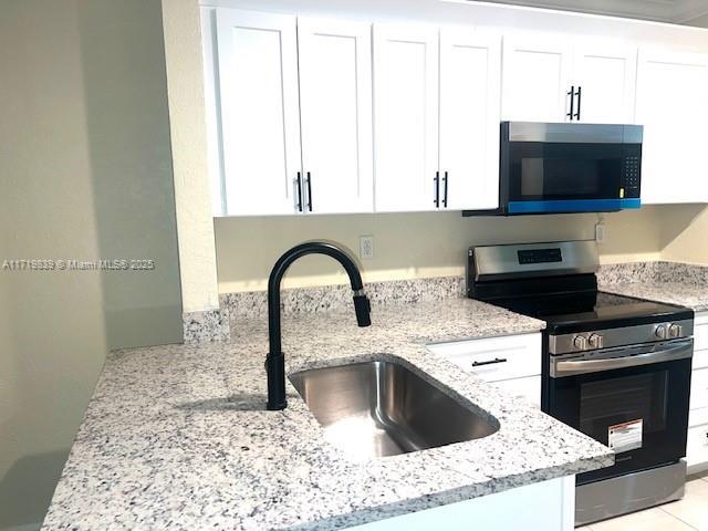 1574 NW 7th Ln, Pompano Beach, FL 33060 - kitchen featuring electric stove, white cabinetry, and light stone counters