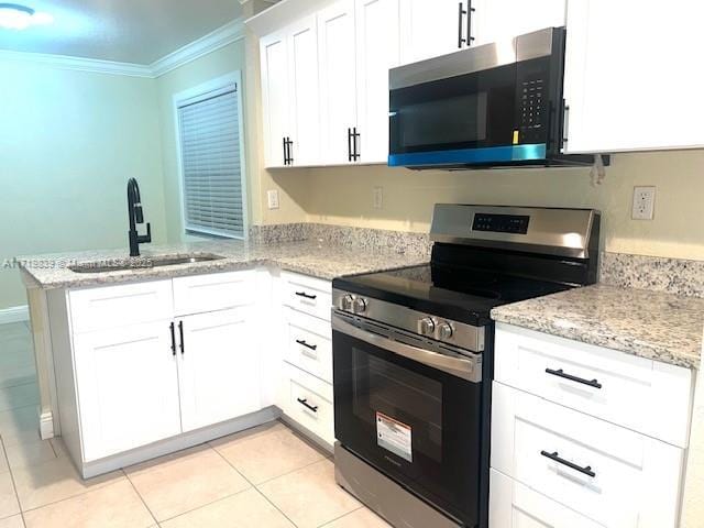 1574 NW 7th Ln, Pompano Beach, FL 33060 - kitchen featuring appliances with stainless steel finishes, ornamental molding, a peninsula, light tile patterned floors, and white cabinetry