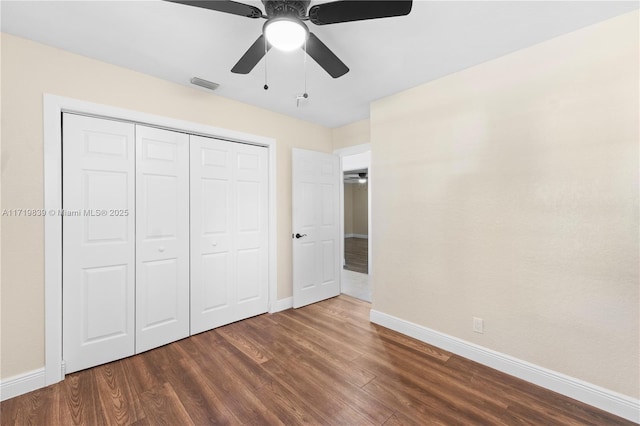 unfurnished bedroom with ceiling fan, dark wood-type flooring, and a closet