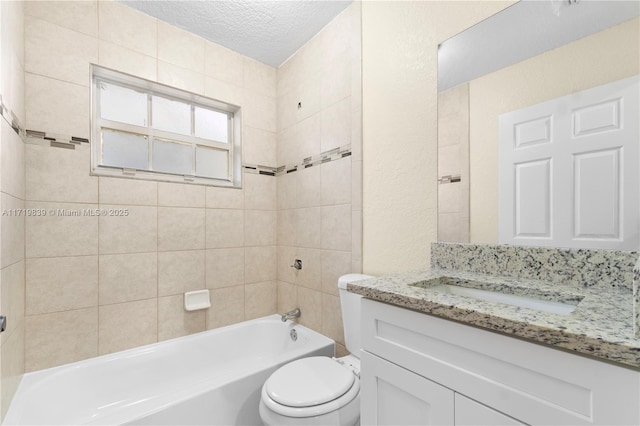 full bathroom with vanity, a textured ceiling, tiled shower / bath combo, and toilet