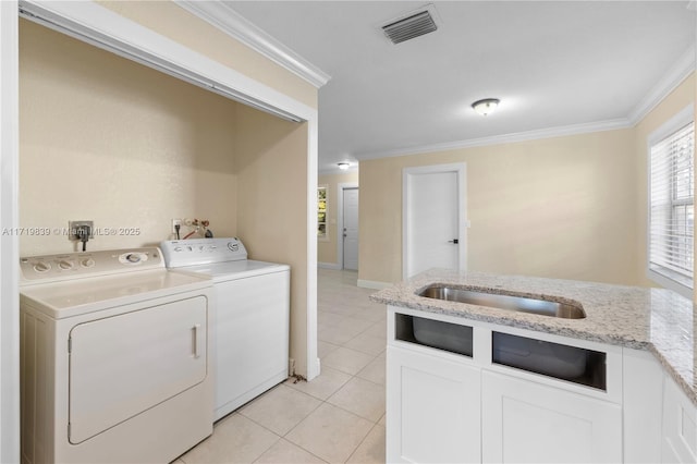 laundry area with washing machine and clothes dryer, crown molding, sink, and light tile patterned floors