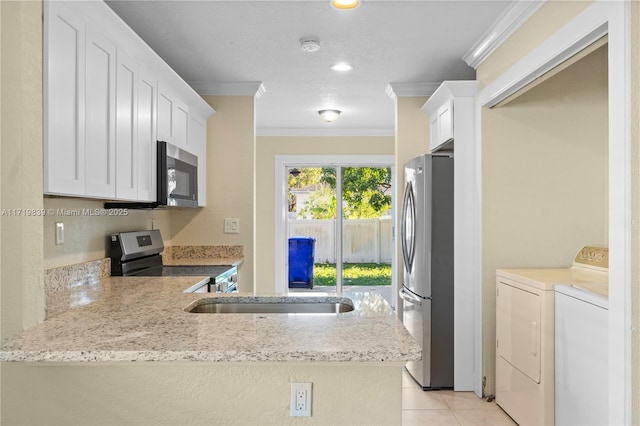 kitchen with white cabinetry, kitchen peninsula, appliances with stainless steel finishes, and washing machine and clothes dryer