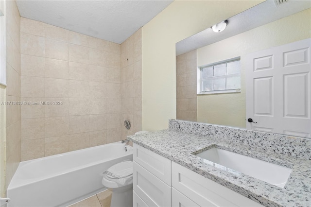 full bathroom with vanity, tile patterned floors, tiled shower / bath combo, toilet, and a textured ceiling