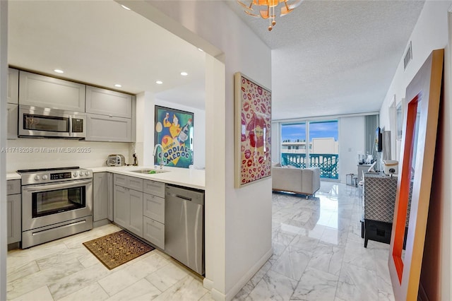 kitchen featuring backsplash, gray cabinets, sink, and appliances with stainless steel finishes